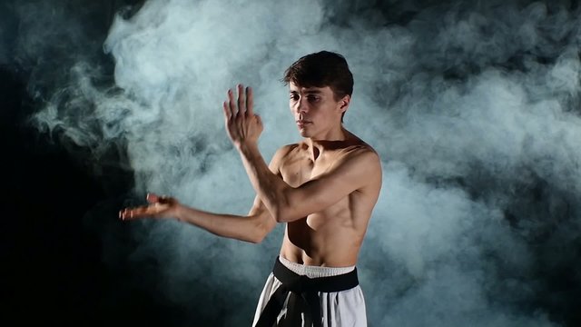 Man training taekwondo or karate with a naked torso and a black