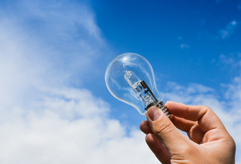 Mano con lampadina su cielo blu