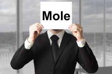 businessman hiding face behind sign mole