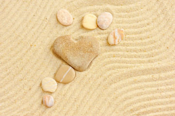 Fototapeta na wymiar Heart shaped stone is on sand