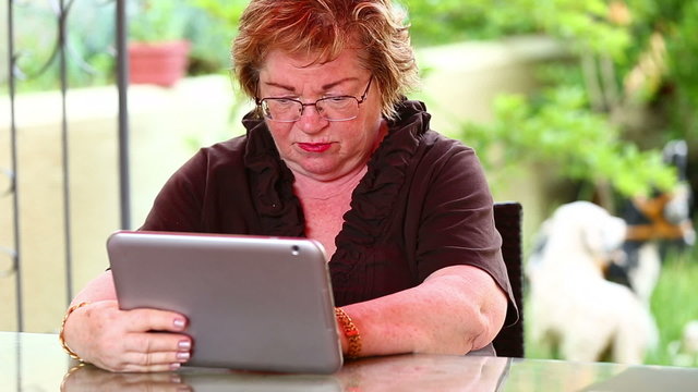 senior woman using digital tablet in a garden