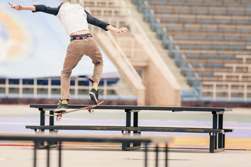 teenager doing a trick by skateboard on a rail in skate park