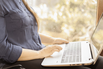 Beautiful happy student with a laptop sitting against window