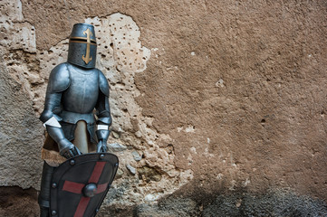 Medieval knight armour in front of textured stone wall