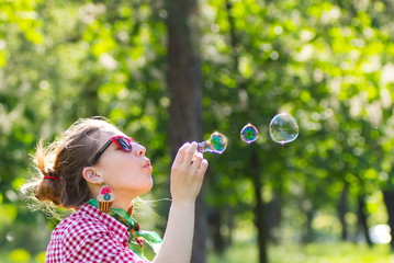 Cheerful beautiful brunette girl in glasses blowing soap bubbles