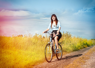 Obraz premium Funny girl with bicycle in a country road.