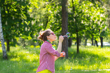 Cheerful beautiful brunette girl in glasses blowing soap bubbles