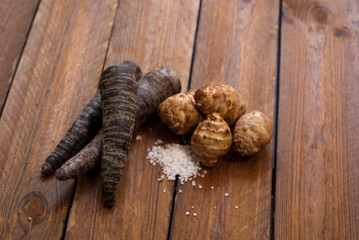 purple carrots and jerusalem artichokes with salt on raw wooden table