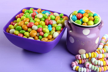 Colorful candies in a bowl on a wooden background