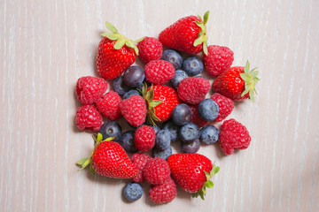 raspberry, strawberry and bilberry on the wooden background