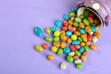 Colorful candies in a bowl on a wooden background