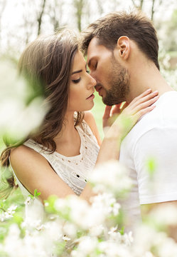 Portrait of kissing couple in the blooming garden