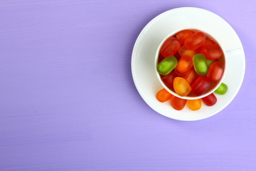 Colorful candies, jelly candies in a white cup on a wooden background