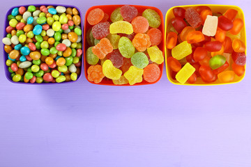 Colorful candies in a bowl on a wooden background