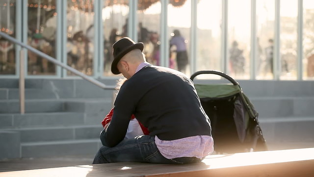 A little girl runs up and hugs her dad, then he ties her shoe lase