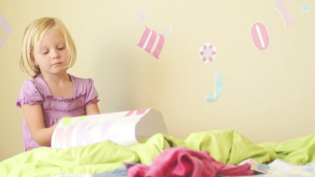 A young girl puts decals on her bedroom wall