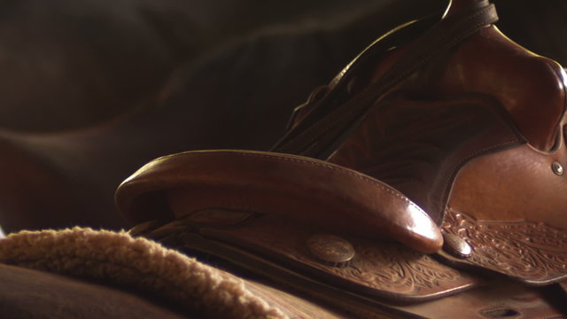 Close up of a saddle sitting on a horse and a girl adjusting it