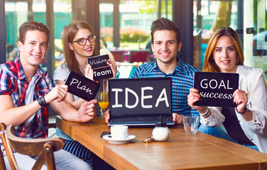 Group of young people sitting at a cafe, holding electronic gadgets with messages