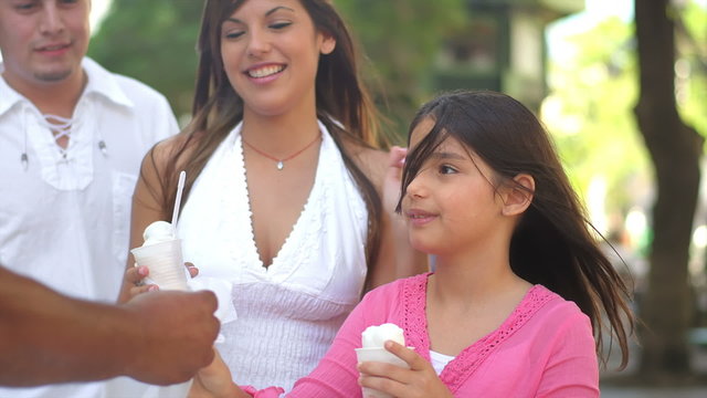 A young girl eats ice cream with her family