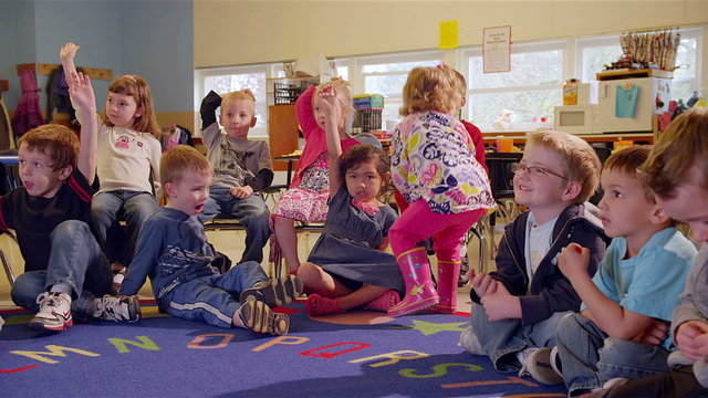 A cute group of preschool students sit together in class and sing a song