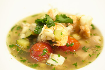 soup with fish, tomatoes, zucchini, herbs