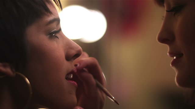 Close up shot of female model getting lipstick applied to her lips