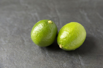 Two fresh limes on slate background