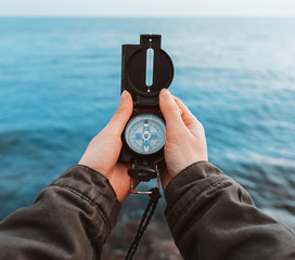 Tourist searching direction with a compass on coast