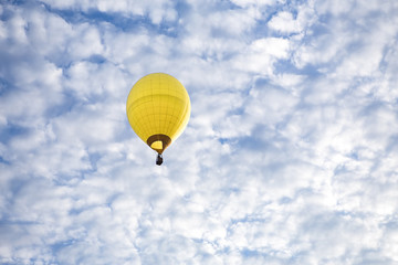 Fototapeta premium A Yellow Hot Air Balloon floats high in the sky. 