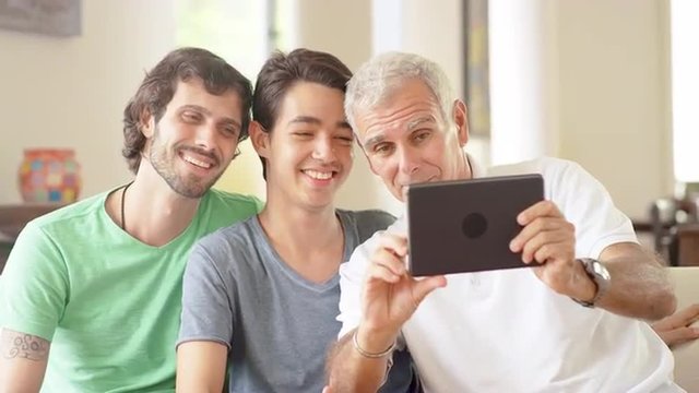 Grandfather using a tablet computer to take pictures with grandchildren