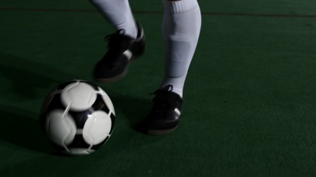 Close up of a soccer player's feet as he dribbles and does tricks with a ball