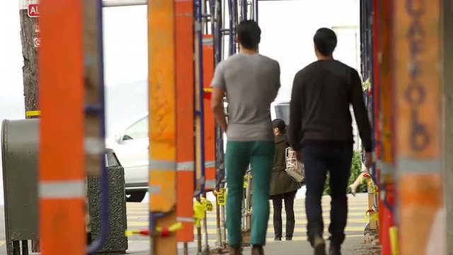 Two men walk down the street in San Francisco under a construction site