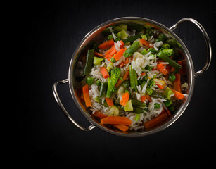 Rice with vegetables on  black background.