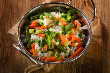 Rice with vegetables on  wooden table.