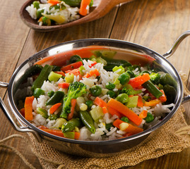 Rice with vegetables on a rustic wooden background.