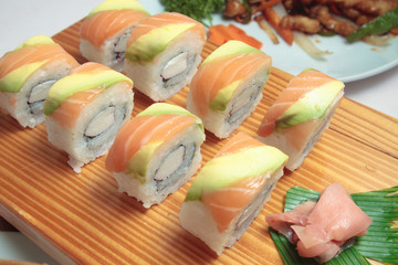 sushi with salmon and avocado on wooden plate