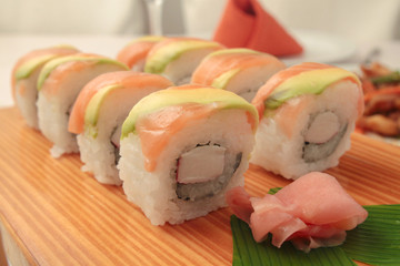 sushi with salmon and avocado on wooden plate