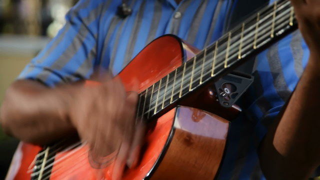 A man plays guitar on the street for money