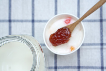 Milk ice cream in white cup with Spoon of strawberry jam backgro
