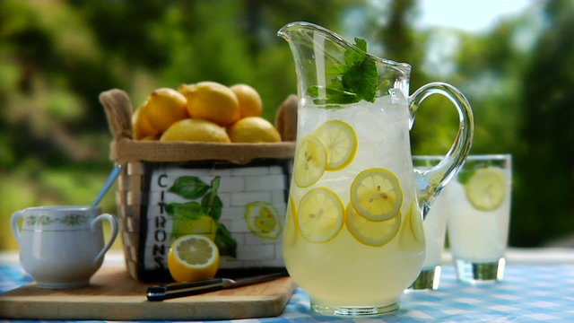 pitcher of lemonade and glasses setting on a table outside 