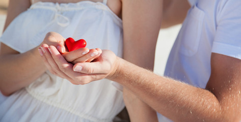 Hands of man and woman holding red heart