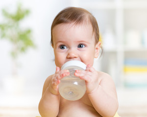 sweet baby holding bottle and drinking water