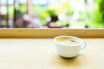 Espresso Coffee cup on wood table in cafe with blur green garden