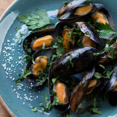 Fototapeta na wymiar Close-up of steamed mussels with chopped parsley and sea salt