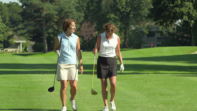 Golfers walk down the fairway talking and laughing together. 