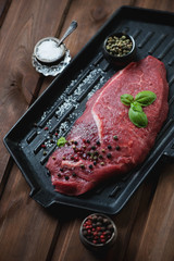 Raw beef barbecue steak on a cast-iron grill, high angle view