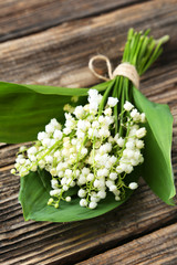 Lily of the Valley with leaves on brown wooden background