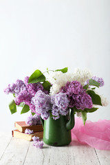 Beautiful lilac in pitcher on white wooden background