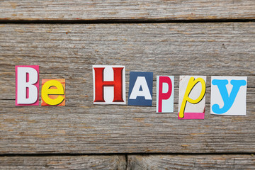 The word be happy in cut out magazine letters