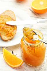 Bread with orange jam on white wooden background